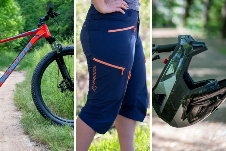 Image showing a mountain bike, a pair of navy shorts with orange zippered pockets, and a black helmet. The bike is positioned on a dirt path with greenery in the background. The shorts feature the Norrona brand logo, and the helmet is designed for cycling safety.