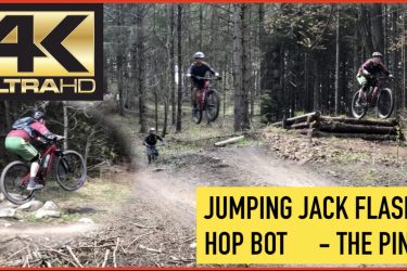 Alt text: "A vibrant image featuring mountain bikers jumping and riding trails in a forested area. The top left corner displays a '4K Ultra HD' logo, while the bottom of the image has text reading 'JUMPING JACK FLASH & HOP BOT - THE PINES'." The Pines mountain bike trail.