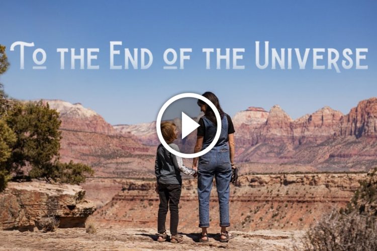 A woman and a child stand side by side at the edge of a scenic viewpoint, overlooking a vast landscape of red rock formations and mountains under a clear blue sky. Above them, the text "To the End of the Universe" is displayed prominently, accompanied by a play button symbol.