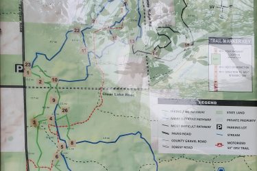 Map of the Ogemaw Hills Pathway, displaying various marked trails for hiking and skiing. The map includes a key indicating different trail difficulties, parking locations, and surrounding landmarks. Trails are highlighted in blue, green, and red, with distances noted next to each segment. Directions and orientation through the area are also provided. Ogemaw Hills Pathway mountain bike trail.