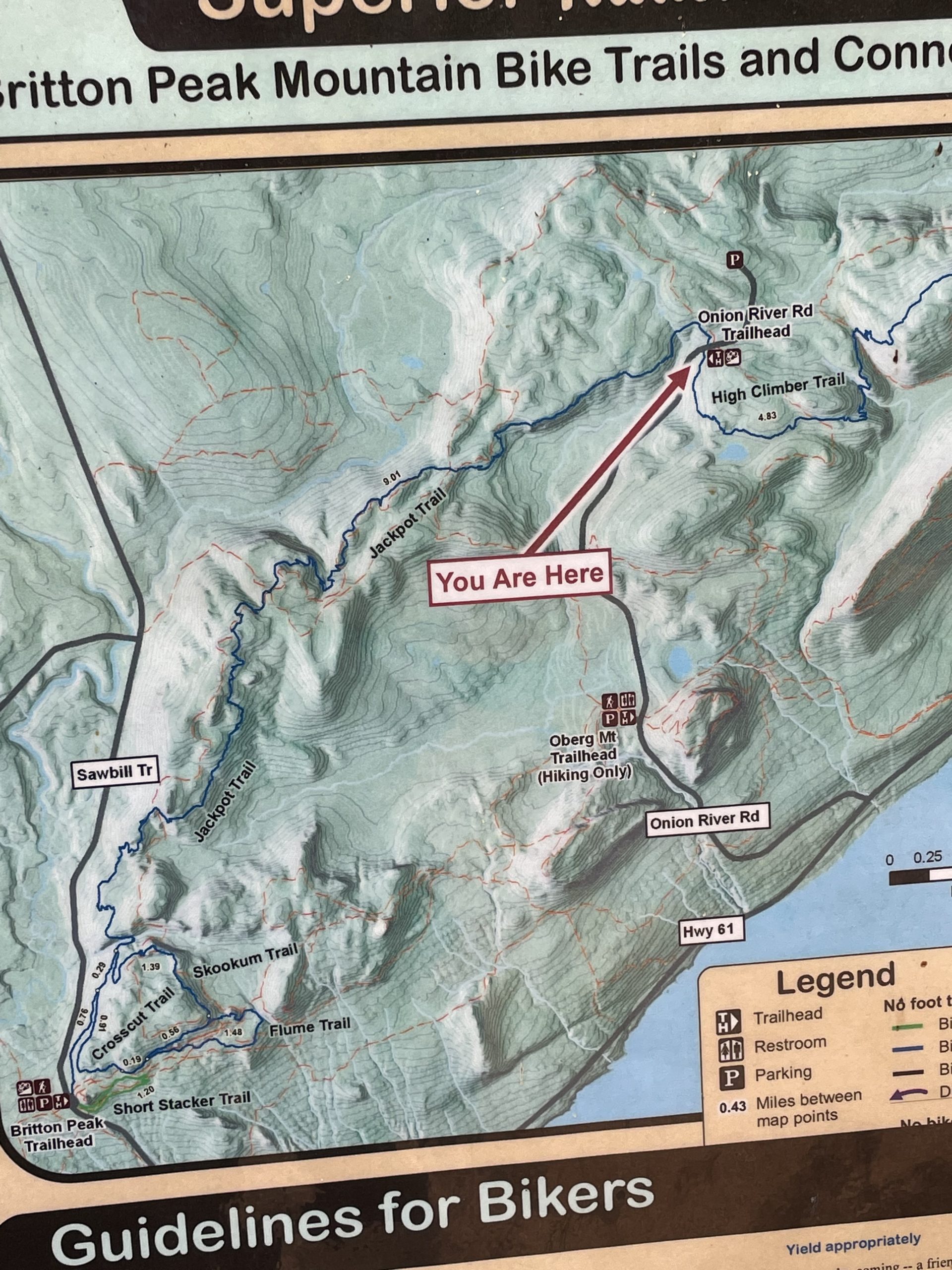 Map of Britton Peak Mountain Bike Trails highlighting various biking routes and trailheads, with a marker indicating "You Are Here." The map includes features like trail names, locations of restrooms and parking, and guidelines for bikers. Jackpot mountain bike trail.