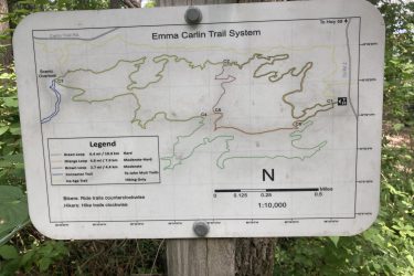 Map of the Emma Carlin Trail System, showing various trail loops and their difficulty levels, with a legend indicating trail designations for bikers and hikers. Includes details such as distance in miles and kilometers for each loop, with a note on the direction of travel for bikers and hikers. Kettle Moraine John Muir + Emma Carlin mountain bike trail.