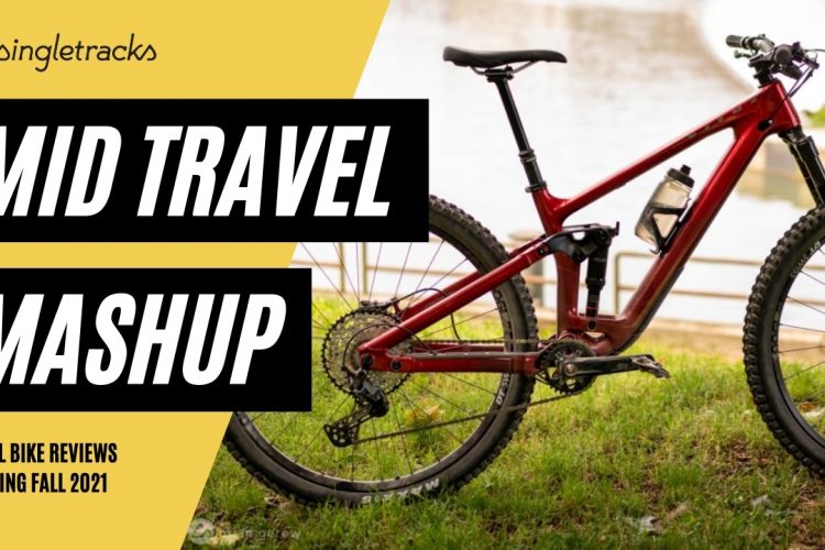 A mountain bike with a sleek red frame is displayed on a grassy area near a body of water. Bold text overlays the image, reading "MID TRAVEL MASHUP" and "TRAIL BIKE REVIEWS COMING FALL 2021". The bike features thick tires and a water bottle holder, emphasizing its suitability for trail riding.