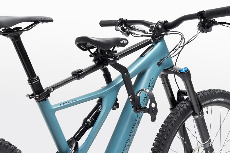 Close-up of a mountain bike showcasing a sleek, turquoise frame, adjustable seat post, and components such as handlebars and suspension fork. The image highlights the modern design and features of the bike, suitable for off-road cycling.