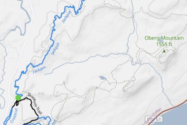 Map showing hiking trails near Oberg Mountain, featuring the "Jackpot," "Skookum Trail," and "Short Stacker" paths. Key elevation points are indicated, including Carlton Peak at 1526 ft and Oberg Mountain at 1555 ft. Major roads and nearby bodies of water are marked, with a scale of 1 mile provided for reference. Jackpot mountain bike trail.