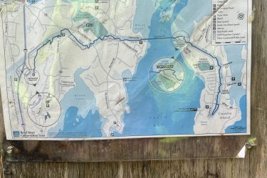 Map of the West Side Trail showing various hiking routes and points of interest in the Town of Yarmouth, including parking areas and recreational sites. The map is enclosed in a protective cover and attached to a wooden post. West Side Trail mountain bike trail.