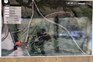 A detailed map indicating the trails and points of interest in the Oregon and California National Historic Trails area. The map includes labeled hiking trails, identified parking lots, and points of interest such as overlooks and campsites, with a marked location showing "You Are Here." Features include the Big Blue River and various meadows, along with a legend for orientation. Alcove Springs mountain bike trail.