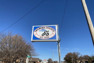 Sign for Trailwind Cyclists, established in 2000, featuring a bicycle graphic and blue skies in the background.