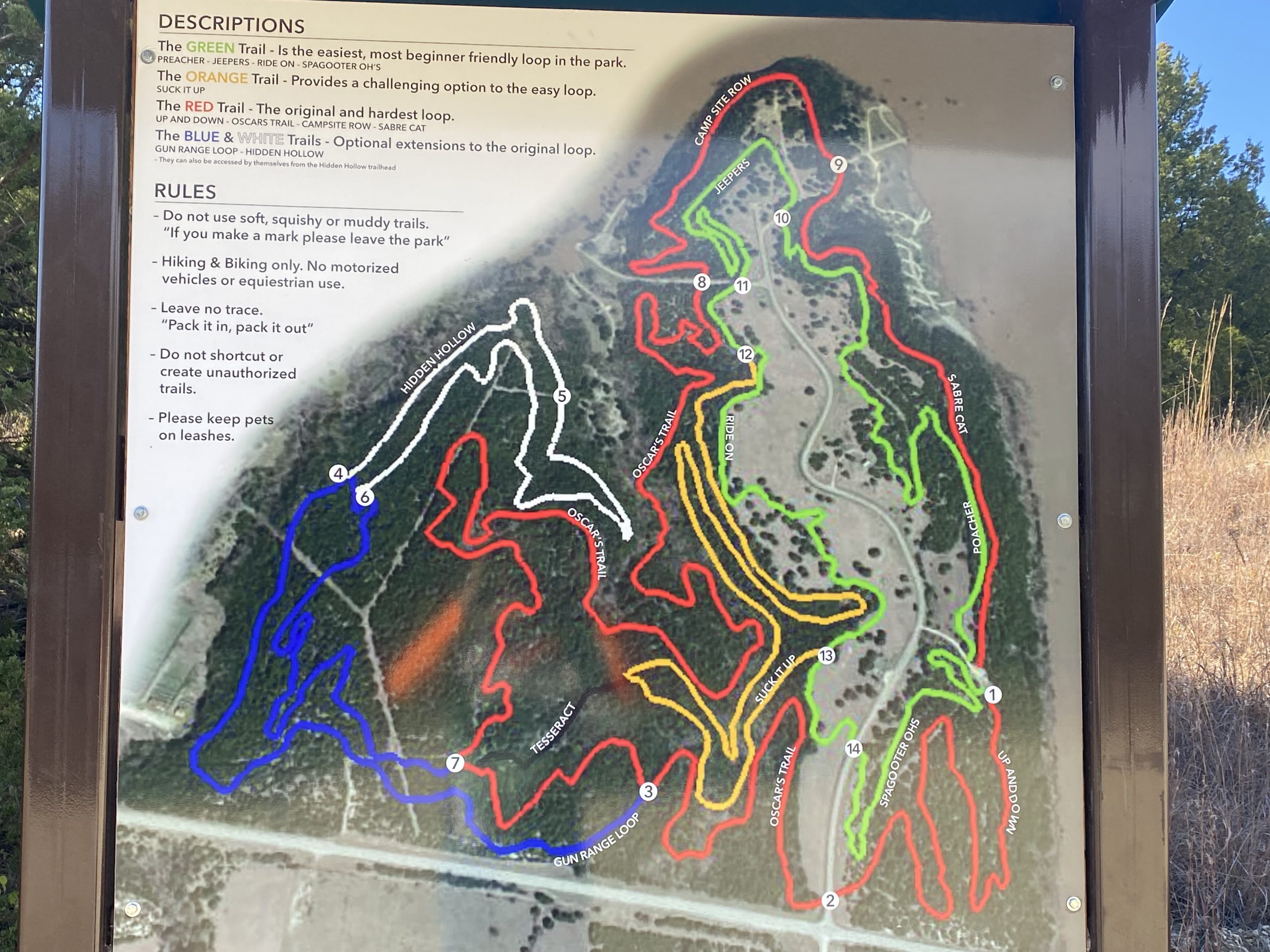 Map of a trail system showing various hiking and biking paths. The trails are color-coded: green for the easiest loop, orange for a moderate option, red for the original and hardest loop, and blue and white for optional extensions. Key rules include leaving no trace, keeping pets on leashes, and avoiding unauthorized trails. Descriptions of each trail are provided alongside the map. Fancy Creek State Park mountain bike trail.