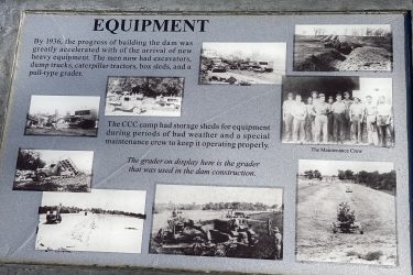Image of a historical information plaque titled "Equipment," featuring text about the construction of a dam in 1936. The plaque includes photographs of heavy machinery, including excavators, dump trucks, and a grader, alongside images of a maintenance crew and various stages of construction. The overall layout emphasizes the importance of equipment in the dam-building process. Drywood Creek Trail mountain bike trail.