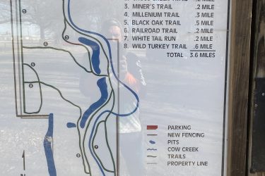 Trail guide map displaying various trails, their lengths, and other features. The map includes the following trails: Cassaletto Loup (1.4 miles), Cross Creek Trail (2 miles), Miner's Trail (0.2 miles), Millennium Trail (0.3 miles), Black Oak Trail (0.5 miles), Railroad Trail (0.2 miles), White Tail Run (0.2 miles), and Wild Turkey Trail (0.6 miles), totaling 3.6 miles. Additional features such as parking, new fencing, and Cow Creek are also marked. Wilderness Park Trails mountain bike trail.