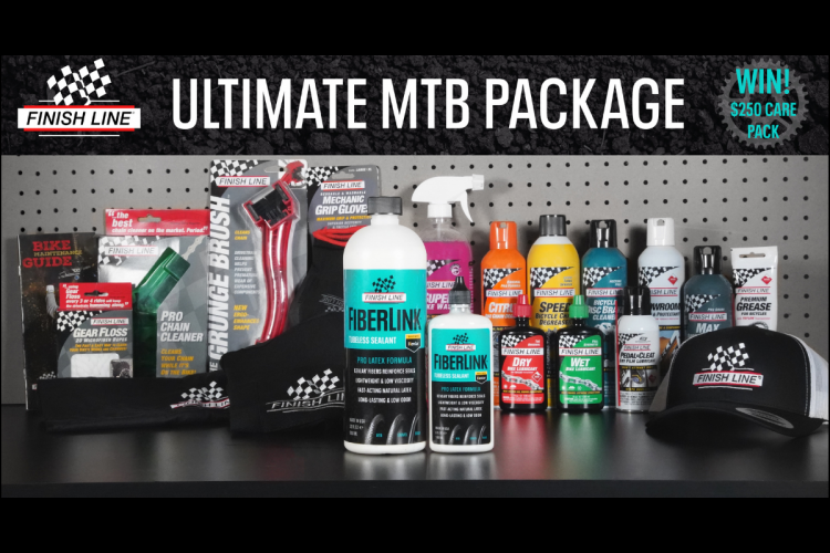 Alt text: An assortment of bicycle maintenance products displayed on a pegboard, including cleaning sprays, lubricants, and tools, with a cap and a promotional banner for the "Ultimate MTB Package."