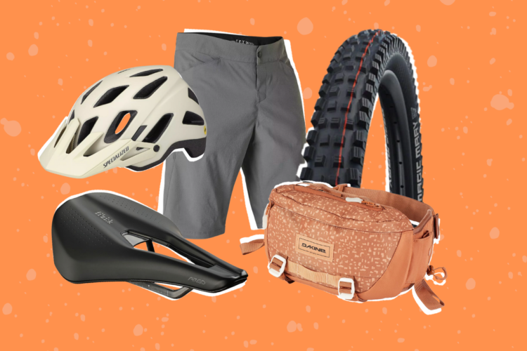 A collection of cycling gear including a white helmet, gray shorts, a black bicycle saddle, a mountain bike tire, and an orange Dakine waist bag, set against a vibrant orange background with a speckled texture.