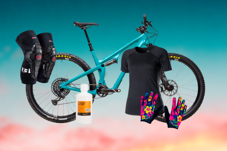 A mountain bike in vibrant teal color, accompanied by protective knee pads, a black cycling shirt, floral-patterned gloves, and a bottle of bicycle sealant. The background features a colorful gradient transitioning from teal to pink.