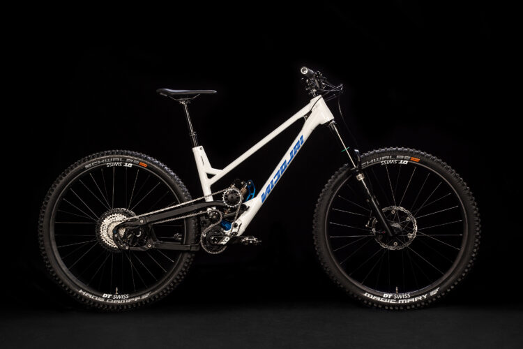 A white mountain bike with black wheels and components is displayed against a black background. The bike features a prominent suspension system, wide tires designed for grip, and a sleek frame with blue accents. The handlebars are positioned high, and the seat is adjustable, showcasing its design for off-road performance.