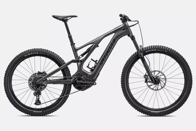 A sleek, black electric mountain bike with wide tires, front suspension, and a minimalist design, featuring a prominent "Specialized" logo on the frame. The bike is positioned against a light gray background.