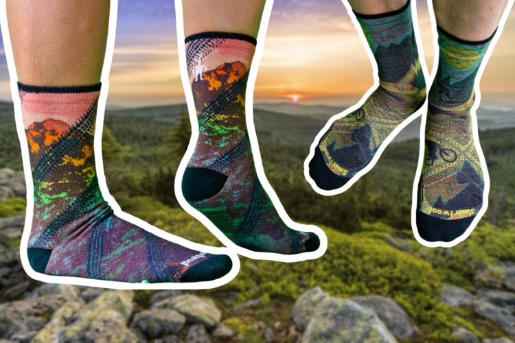 Colorful patterned socks displayed against a scenic outdoor background, featuring mountains and a sunset. The socks showcase intricate designs in green, blue, red, and yellow, with a focus on outdoor adventure themes.