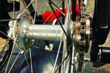 Close-up of a bicycle rear hub featuring the brand name "Paul" and the designation "USA 28," with visible spokes, a portion of the chain, and part of the bike frame in the background.