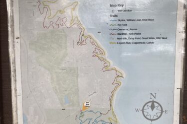 Map of the Perry Lake Mountain Bike Trails, showing various trails and junctions. The map includes a key indicating trail types, with marked trails such as Skyline, Kid Rock, Blackfoot, and Logan's Run. A "You Are Here" marker is also indicated on the map. Orientation is provided with a compass rose showing north. The surrounding area features a mix of trails and natural landscapes. Perry Lake Bike Trail mountain bike trail.