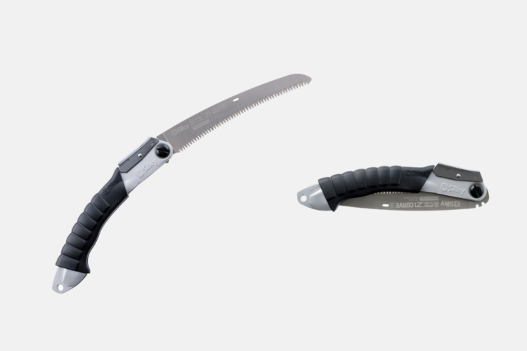 A folding saw with a curved blade featuring a serrated edge, positioned beside its closed handle. The saw has a black rubber grip for improved handling and a metallic finish for durability.