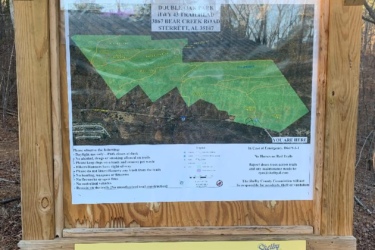 Map and information sign at Double Oak Park, located at 3867 Bear Creek Road, Sterrett, Alabama. The map details the park's trail layout, safety guidelines, and emergency contact information. A wooden sign at the bottom encourages exploration of the park. Double Oak mountain bike trail.