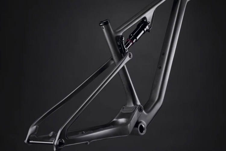 Mountain bike frame in a sleek black design, showcasing a modern suspension system. The frame is positioned against a dark background, emphasizing its angular lines and engineering details.