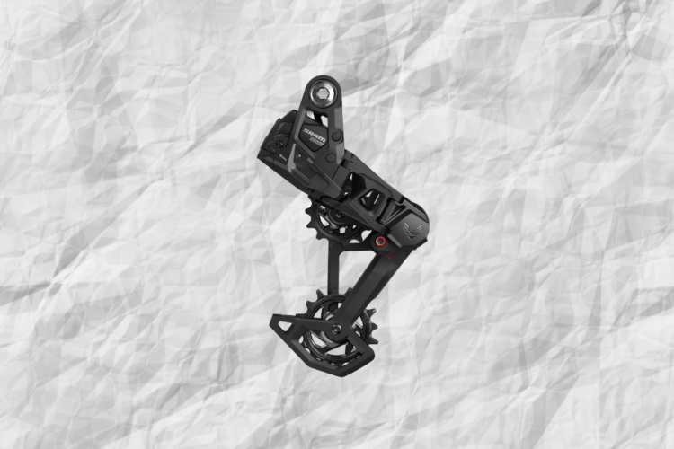 Alt text: "A black bicycle rear derailleur positioned against a textured, crumpled white background. The component features intricate mechanical details and a sleek design."