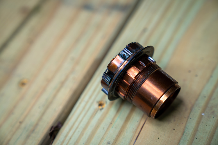 A close-up image of a copper-colored plumbing connector resting on a wooden surface, showcasing its detailed texture and design.