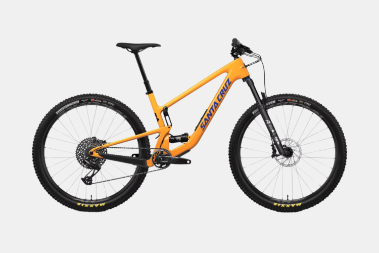 Alt text: A bright orange mountain bike with a lightweight frame, featuring wide tires, a dropper seat post, and a Shimano gear system, displayed against a plain background.