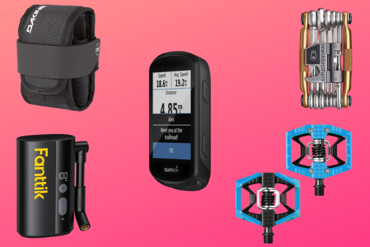 A collection of bike accessories displayed on a pink gradient background, including a small pouch, a Garmin GPS device showing speed and distance metrics, a portable air pump, a multi-tool, and a pair of blue bike pedals.