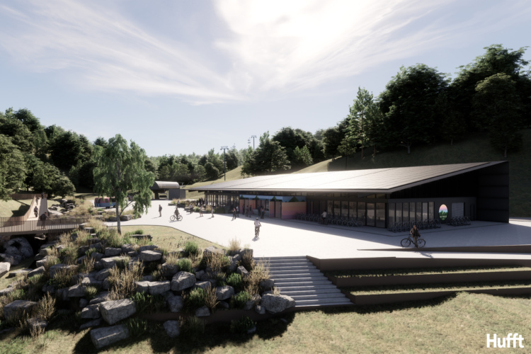 A modern building set in a scenic outdoor environment, featuring large glass windows and a sleek roof design. In the foreground, people are seen walking, biking, and enjoying the space, while lush greenery and rocks adorn the landscape. A pathway leads up to the entrance, with trees and hills in the background. The sky is bright with scattered clouds.