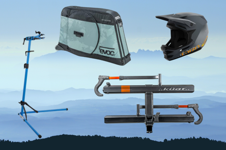 Image depicting bicycle-related gear, including a blue bike repair stand, a gray bike travel bag, a black helmet, and a bike rack. The background features a soft gradient of mountain landscapes.