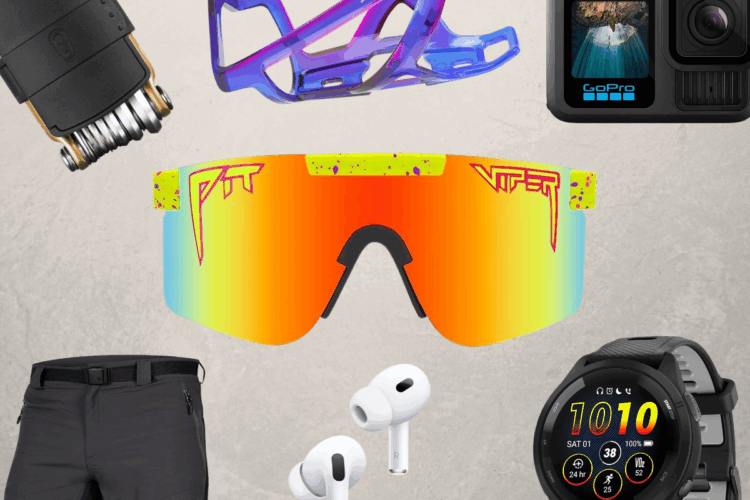 A flatlay featuring a collection of outdoor and sports gear, including a colorful pair of sunglasses with a reflective lens, a bike water bottle holder, a GoPro camera, white wireless earbuds, a smartwatch displaying fitness stats, and a pair of black outdoor shorts, all arranged on a neutral background.