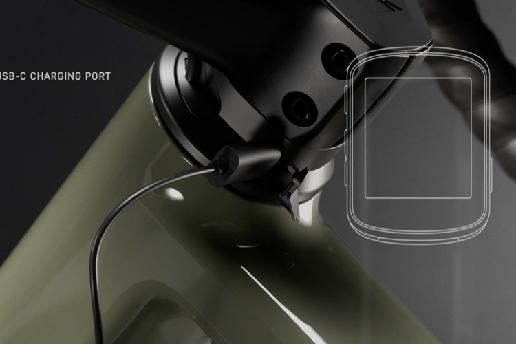 Close-up of a USB-C charging port on a bicycle frame, featuring a black charging cable connected to the port. The background is dark, emphasizing the sleek design of the bike and the charging components. Text labeled "USB-C CHARGING PORT" is included in the image.