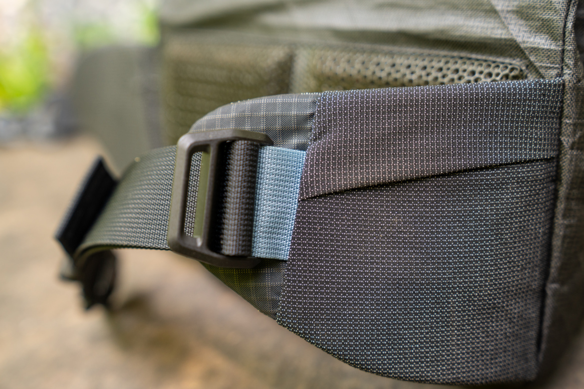 Close-up of a textured strap and buckle on a fabric bag, showcasing the stitching and materials used in its design.