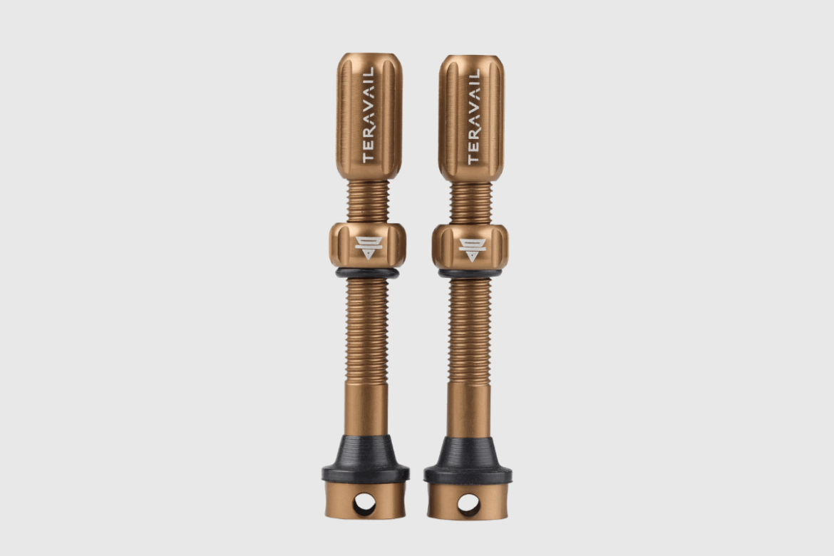A pair of gold and black bicycle valve extenders designed for enhancing tire inflation accessibility. The extenders feature a textured grip for ease of use and are mounted on threaded metal bases, suitable for various valve types.