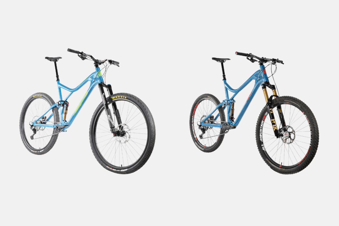 Two mountain bikes, 32er left and 29er right, are displayed side by side. Both have a similar blue frame, but differ in fork design. The left bike features a black suspension fork, while the right bike has a gold suspension fork. Each bike is equipped with thick tires and disc brakes, suitable for off-road cycling. The background is plain white, emphasizing the bikes' designs.