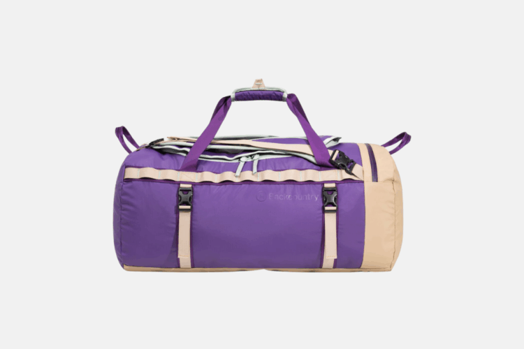 A durable duffel bag featuring a vibrant purple body with beige accents and straps, designed for travel or outdoor activities. The bag has dual handles and side buckles for secure closure, along with a zippered top for easy access to contents.
