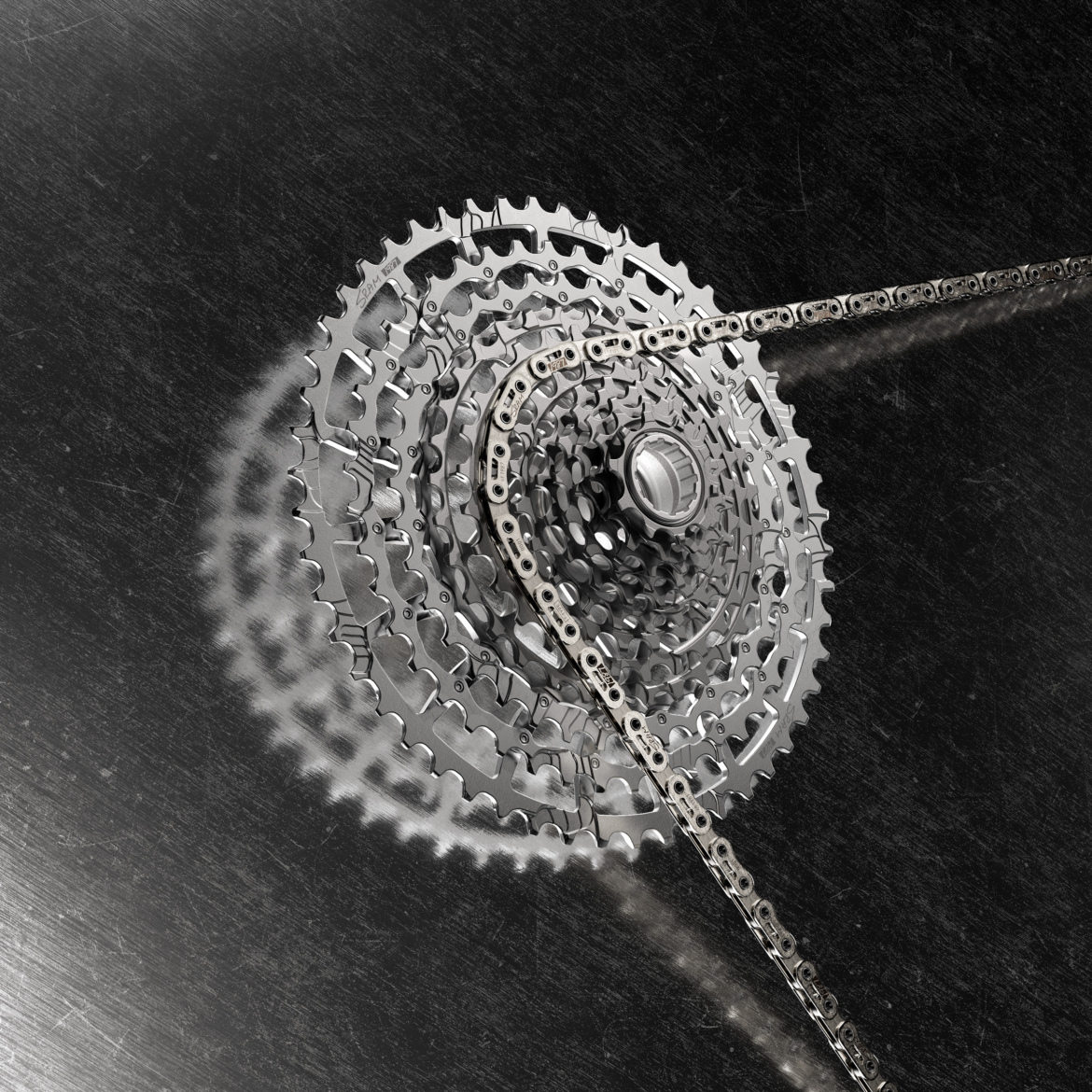 A close-up view of a bicycle's derailleur system featuring a shiny, multi-layered cassette and chain, set against a dark metallic background.
