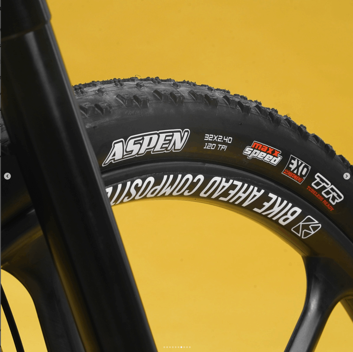 Close-up of a mountain bike tire showing the tread and branding, including "Aspen" with specifications of 32x2.40 size and 120 TPI, set against a bright yellow background. The tire has labels indicating features such as "maxx Speed," "EXO," and "TR Tubeless Ready."