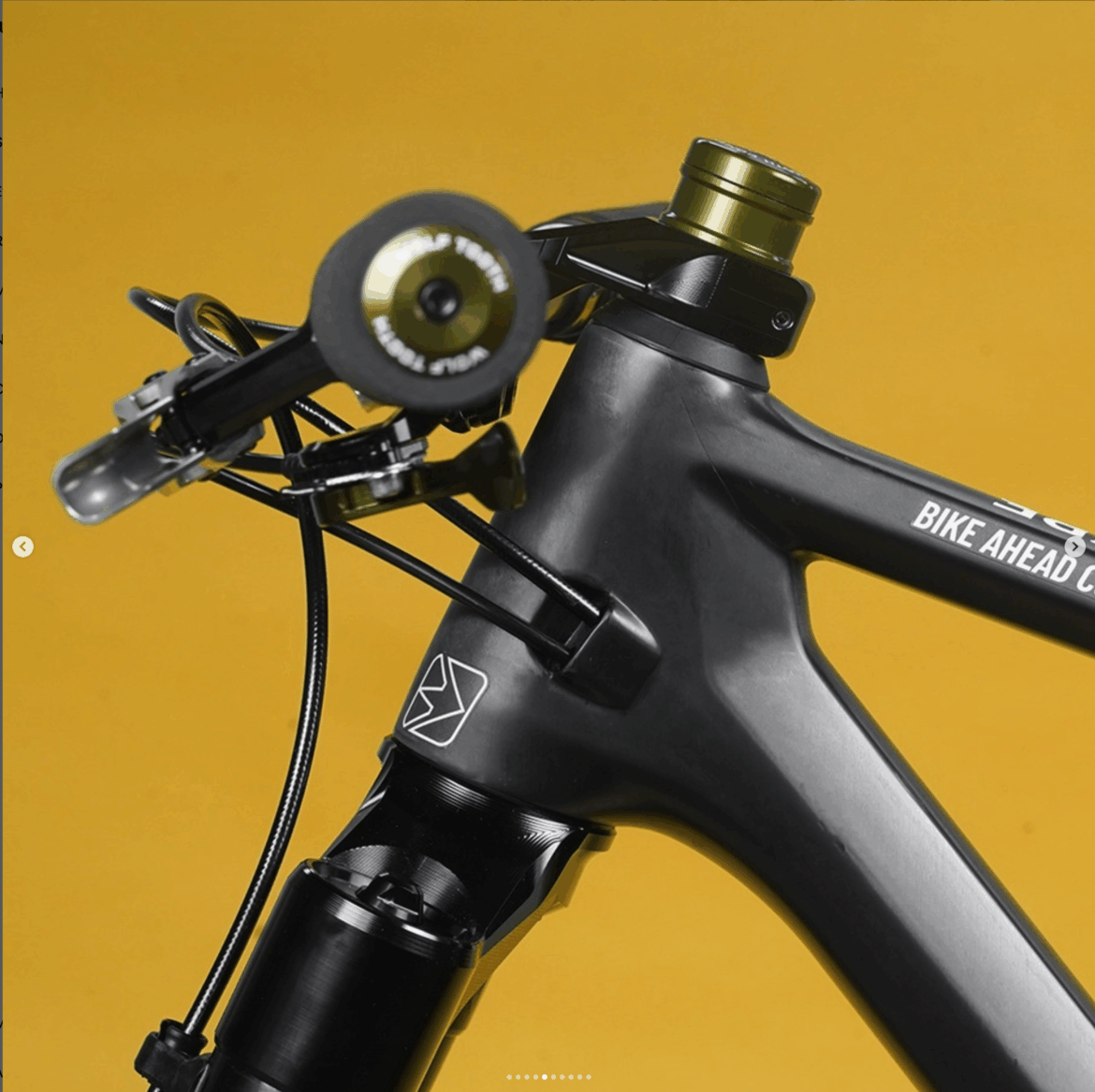 Close-up of a black bicycle frame highlighting the handlebar, stem, and suspension components, set against a vibrant yellow background.