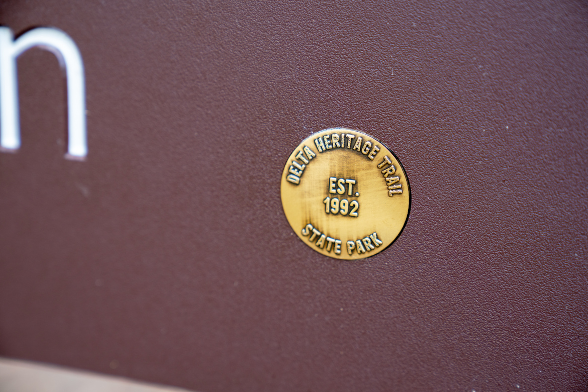 A close-up view of a bronze plaque displaying "Delta Heritage Trail," "EST. 1992," and "State Park," set against a brown background.