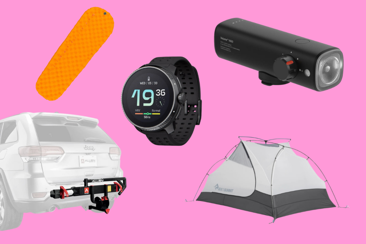 A flat lay image featuring various outdoor and camping gear on a pink background, including an orange sleeping pad, a black smartwatch displaying data, a portable black light, a hitch-mounted bike rack attached to a white Jeep, and a grey and white tent.