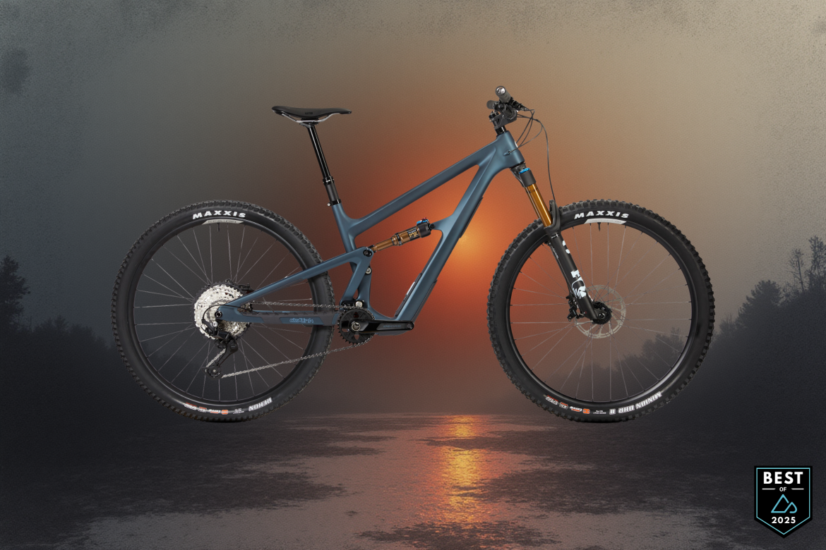A mountain bike with a sleek blue frame, featuring thick tires and a suspension system, suspended against a scenic backdrop of a glowing sunset over water. The image includes a "Best of 2025" badge in the corner.