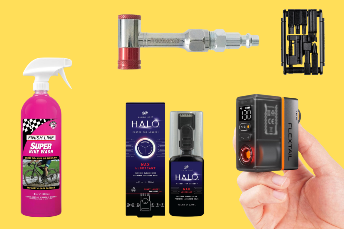 A flat lay of bicycle maintenance products set against a bright yellow background. The image features a spray bottle of "Finish Line Super Bike Wash," a bicycle tool with a red handle, a box of "Halo Wax Lubricant," and a compact air pump in hand, showcasing its pressure gauge. Each item is aimed at ensuring optimal bike performance and maintenance.