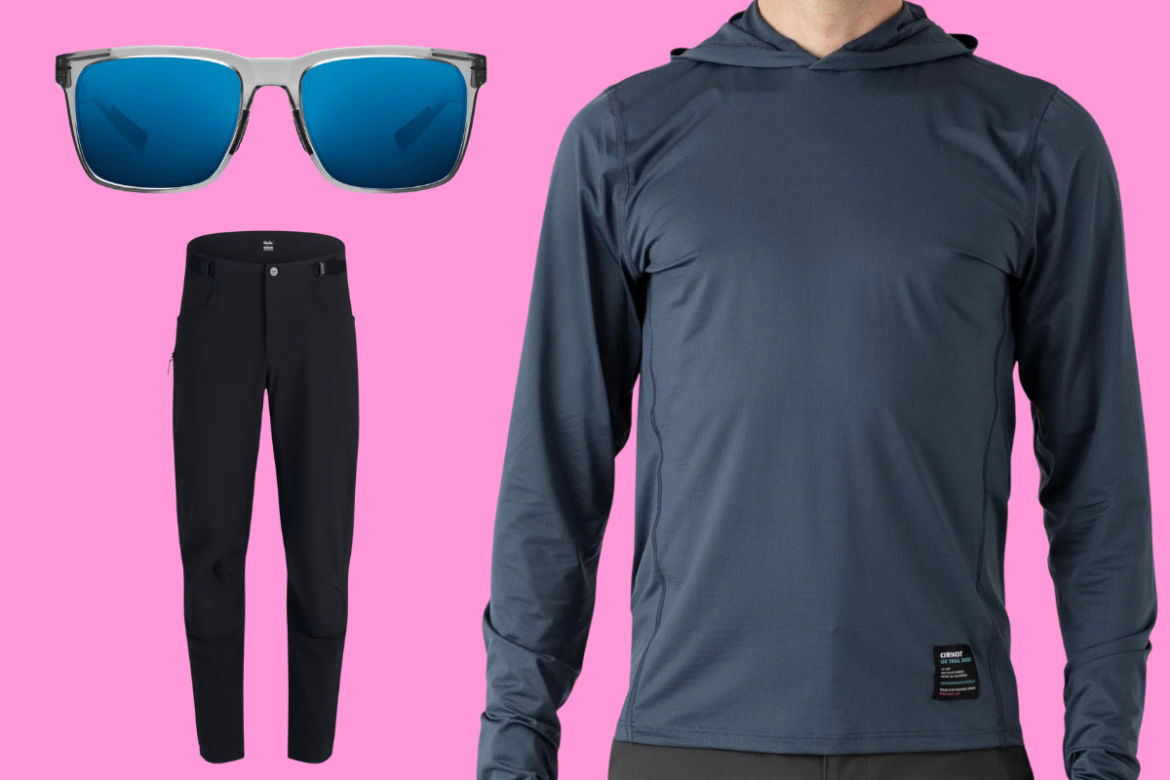 A casual men's outfit featuring a long-sleeve hooded shirt in dark gray, a pair of black outdoor pants, and a pair of sleek sunglasses with blue lenses, all set against a vibrant pink background.