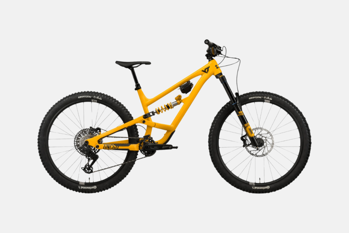 A bright yellow mountain bike with large, knobby tires and a full suspension system, displaying a sleek design and components suitable for rugged terrain. The bike features disc brakes, a prominent shock absorber, and a modern frame style.
