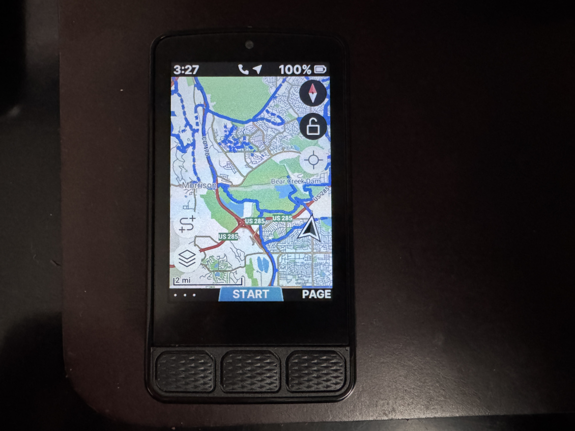 A close-up view of a GPS device displaying a detailed map of a geographical area, with highlighted streets and routes. The screen shows the current time, battery level, and navigation buttons, set against a dark background.