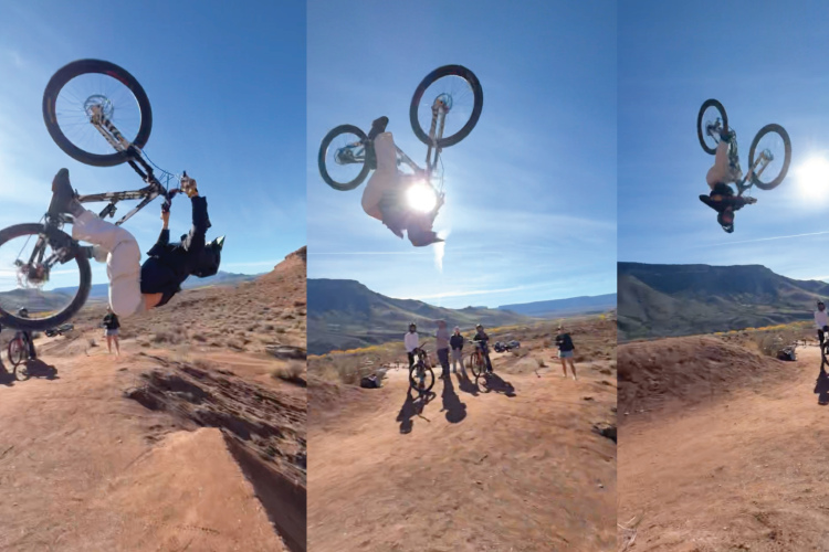 Mountain biker performing a backflip over a dirt ramp, captured in three sequential images. The background features a clear blue sky and rocky terrain, with a group of spectators observing the stunt from a distance.