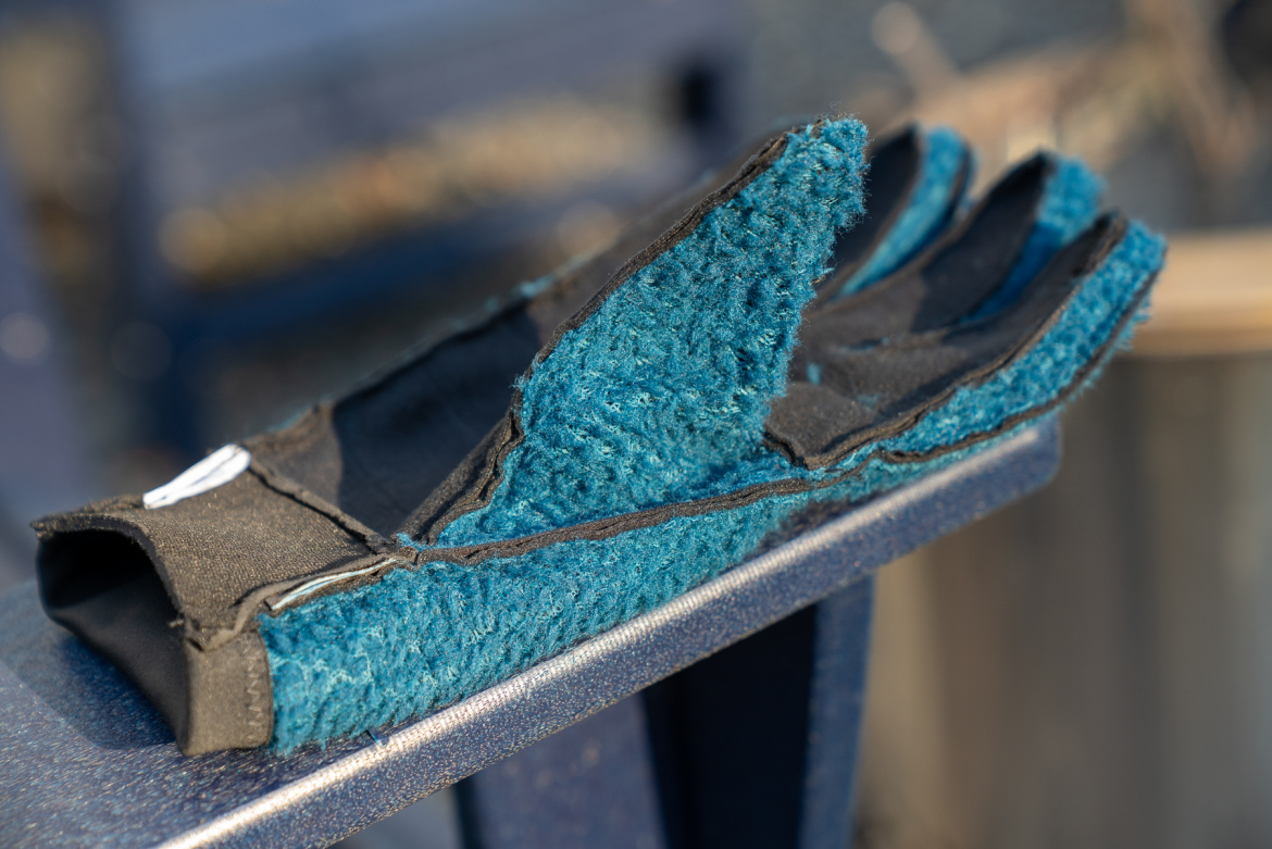 A close-up view of a blue and black glove resting on a surface, showcasing its textured fabric and layered design. The glove appears slightly worn, highlighting its use in manual tasks or outdoor activities.